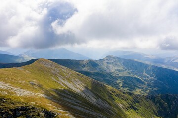 Poster - View of white clouds and blue sky over layered mountain ranges and valley covered with vegetation