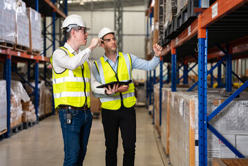 Smart male engineer manager wearing safety vest and helmet using digital tablet checking and assigning work to warehouse workers, Smart teamwork working concept