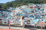 Fototapeta Sypialnia - Woman traveller is sightseeing and looking at Gamcheon Culture Village in Busan, South Korea.