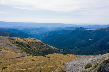 Sticker - View of blue cloudy sky over layered mountain ranges and valley covered with vegetation on sunny day