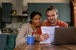© ReeldealHD images - Happy young adult couple at home looking at mortgage application and using a laptop