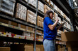 © KANGWANS - A back view of a female worker inspecting items on a shelf in a warehouse. Logistics, business, export, import, logistics. Workers work in warehouses.