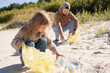 © Julija - happy family activists collecting plastic waste on beach. Volunteers help to keep nature clean up and pick up garbage.
