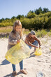 © Julija - Dad and child girl cleaning up the beach pick up plastic bags that pollute sea. Natural education of children. Concept about environmental conservation pollution problems.