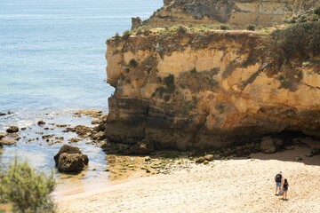 Aerial view of two people walking along the sandy rocky shore of Algarve, Portugal