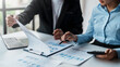 © amnaj - Business people meeting to plan the financial market looking at past quarterly company graph and chart to compare investment and analyze company revenue and marketing strategy.