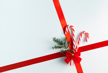 Wall Mural - Christmas candy canes with red ribbon and fir on white background. Minimal holiday gift concept. Flat lay, copy space.