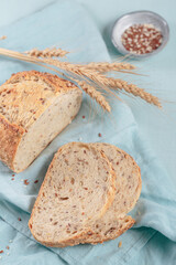 Wall Mural - Sliced fresh baked whole grain bread with flax seeds and sesame seeds on light blue board. Bakery products