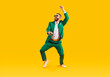 © Studio Romantic - Happy young guy having fun at crazy St Patrick's Day holiday party. Full body shot of funny, cheerful, goofy man wearing green suit and sunglasses dancing isolated on bright yellow colour background
