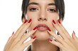 woman shows her red nail polish on a white studio background