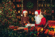 © ZaStock - Little girl assistant packs giftbox with Santa Claus while standing near the table. New Year concept