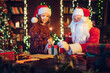 © ZaStock - Little girl helps Santa Claus packs giftbox while standing near the table. Selective focus