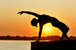 ©  Tatyana Kalmatsuy - Yoga girl practicing side plank position at the sundown river bank
