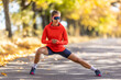 © weyo - Young female athlete in sportswear is warming up before running in the autumn park