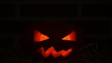 Halloween Pumpkin With Flickering Eyes In Darkness
