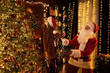© ZaStock - Santa Clause helps his little girl assistant decorating Christmas tree with toys. New Year concept.