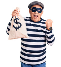 Senior Handsome Man Wearing Burglar Mask Holding Money Bag Screaming Proud, Celebrating Victory And Success Very Excited With Raised Arms