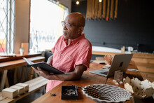 Focused Senior Male Entrepreneur Reading Notebook In Office