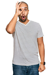 Wall Mural - Hispanic adult man wearing casual clothes doing ok gesture shocked with surprised face, eye looking through fingers. unbelieving expression.