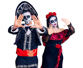 Canvas Print - Young couple wearing mexican day of the dead costume over background doing frame using hands palms and fingers, camera perspective