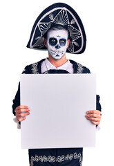 Sticker - Young man wearing day of the dead costume holding blank empty banner thinking attitude and sober expression looking self confident