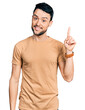 © Krakenimages.com - Hispanic man with beard wearing casual t shirt pointing finger up with successful idea. exited and happy. number one.