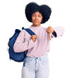 Young african american girl holding student backpack with angry face, negative sign showing dislike with thumbs down, rejection concept