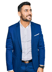 Sticker - Young hispanic man wearing business jacket looking away to side with smile on face, natural expression. laughing confident.