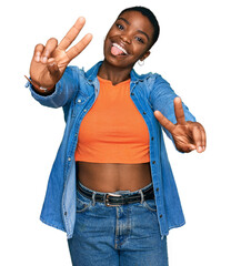 Sticker - Young african american woman wearing casual clothes smiling with tongue out showing fingers of both hands doing victory sign. number two.