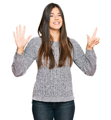 Poster - Young brunette woman wearing casual winter sweater showing and pointing up with fingers number seven while smiling confident and happy.