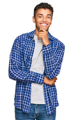 Canvas Print - Young handsome african american man wearing casual clothes looking confident at the camera with smile with crossed arms and hand raised on chin. thinking positive.