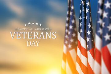 American flags with Text Veterans Day Honoring All Who Served on sunset background. American holiday banner.