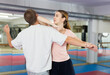 © JackF - Caucasian woman performing elbow strike while sparring with man in gym during self-defence training.