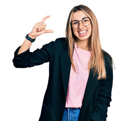 Canvas Print - Hispanic young woman wearing business jacket and glasses smiling and confident gesturing with hand doing small size sign with fingers looking and the camera. measure concept.