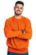 © Krakenimages.com - Young hispanic man with beard wearing casual orange sweater happy face smiling with crossed arms looking at the camera. positive person.