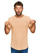© Krakenimages.com - Handsome young man with beard wearing casual tshirt pointing down with fingers showing advertisement, surprised face and open mouth