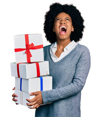 Canvas Print - Young african american woman holding gifts angry and mad screaming frustrated and furious, shouting with anger looking up.