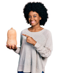 Canvas Print - Young african american woman holding healthy fresh pumpkin smiling happy pointing with hand and finger