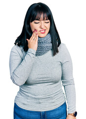 Wall Mural - Young hispanic plus size woman wearing winter scarf touching mouth with hand with painful expression because of toothache or dental illness on teeth. dentist