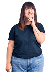 Poster - Young plus size woman wearing casual clothes looking confident at the camera with smile with crossed arms and hand raised on chin. thinking positive.