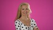 © Robert Peak - Close up of attractive elderly woman entrepreneur looking to camera and smiling. Middle aged confident fashion woman standing and crossing hands. Portrait on pink background.