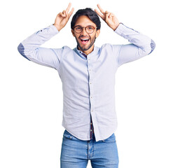 Poster - Handsome hispanic man wearing business shirt and glasses posing funny and crazy with fingers on head as bunny ears, smiling cheerful