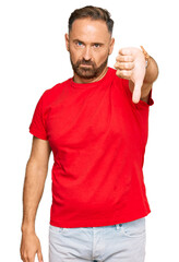 Handsome middle age man wearing casual red tshirt looking unhappy and angry showing rejection and negative with thumbs down gesture. bad expression.