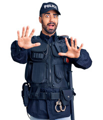 Canvas Print - Young hispanic man wearing police uniform afraid and terrified with fear expression stop gesture with hands, shouting in shock. panic concept.