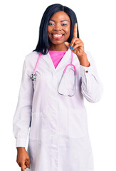 Sticker - Young african american woman wearing doctor stethoscope pointing finger up with successful idea. exited and happy. number one.