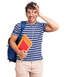 © Krakenimages.com - Young handsome man with curly hair holding student backpack and books smiling happy doing ok sign with hand on eye looking through fingers