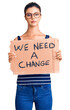 © Krakenimages.com - Young beautiful woman holding we need a change banner thinking attitude and sober expression looking self confident