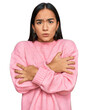 Young asian woman wearing casual winter sweater shaking and freezing for winter cold with sad and shock expression on face