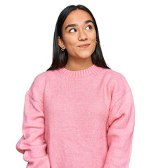 young asian woman wearing casual winter sweater smiling looking to the side and staring away thinkin