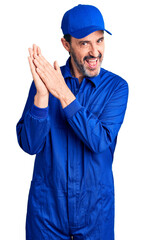 Canvas Print - Middle age handsome man wearing mechanic uniform clapping and applauding happy and joyful, smiling proud hands together